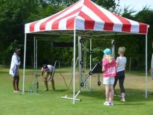 Group of people participating on a giant buzz wire and batak reaction wall games.