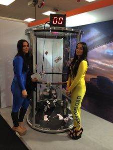 Two female models, standing next to a grab a grand machine at an marketing event.