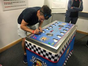 A man playing on the pluck a duck game where he is testing if he has a steady hand and can remove the pieces without sounding the buzzer.