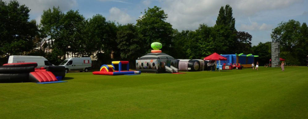 An event complete with various inflatable games, laser tag and rock climbing wall on a grass field