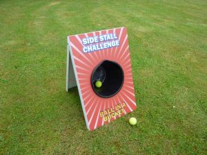 Ball in a bucket game set up as part of a traditional side stall challenge at an event.