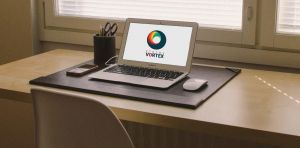 Xtreme Vortex logo displayed on a laptop sitting on a desk in an office.