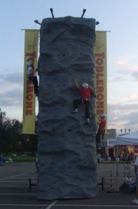 Mobile rock climbing wall with branded banners hung from the side of the trailer. The banners are customised for chocolate company, Toblerone for a family fun day event.