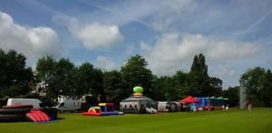 A selection of inflatable activities on a field at a family fun day. Activities include inflatable games, laser tag and rock climbing