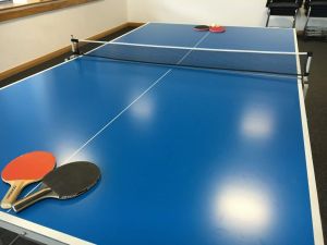 Ping pong table with table tennis bats in a corporate office event.