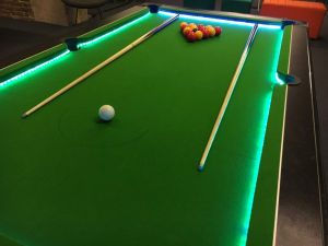 Green pool table hired for an event complete with balls and pool cues.