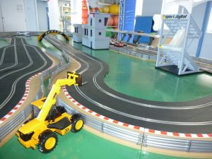 Scalextric track used to create a racing circuit with JCB diggers, buildings and computerised lap time software.