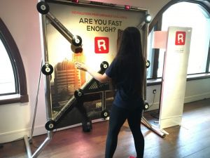 A girl playing on a Batak Reaction Wall complete with branded backdrop and branded magnetic leaderboard.