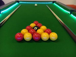 An LED light illuminate the Pool Table complete with pool balls and two pool cues.